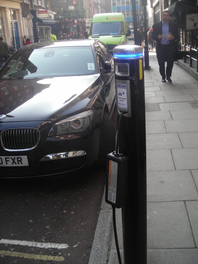 An on-street electric car charging point on Carlisle Street in central London, with a car parked beside it