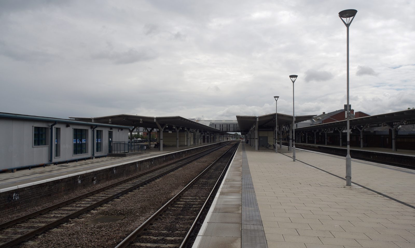 Empty platforms and tracks at Derby railway station under a cloudy sky