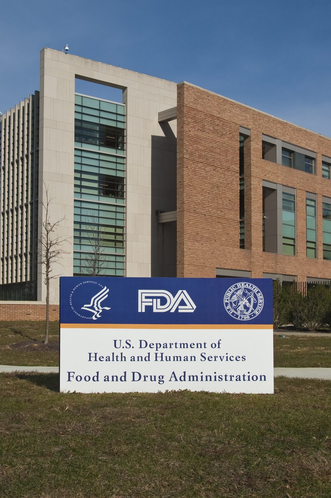 The entrance sign of the U.S. Food and Drug Administration, with Building 21 of its campus behind it