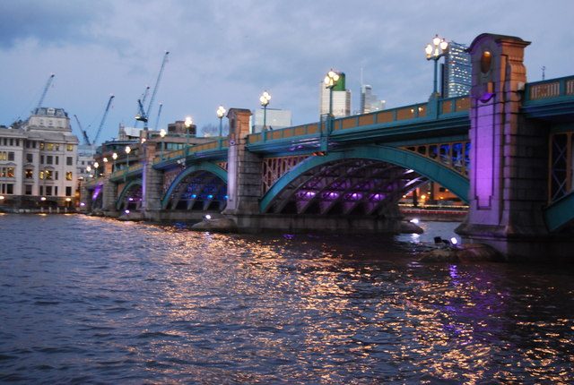 Southwark Bridge over the River Thames in London at dusk, lit in purple