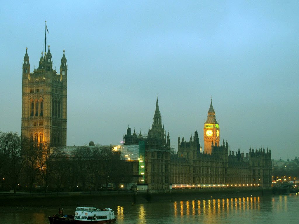The Palace of Westminster seen across the Thames at dusk, with the clock tower lit