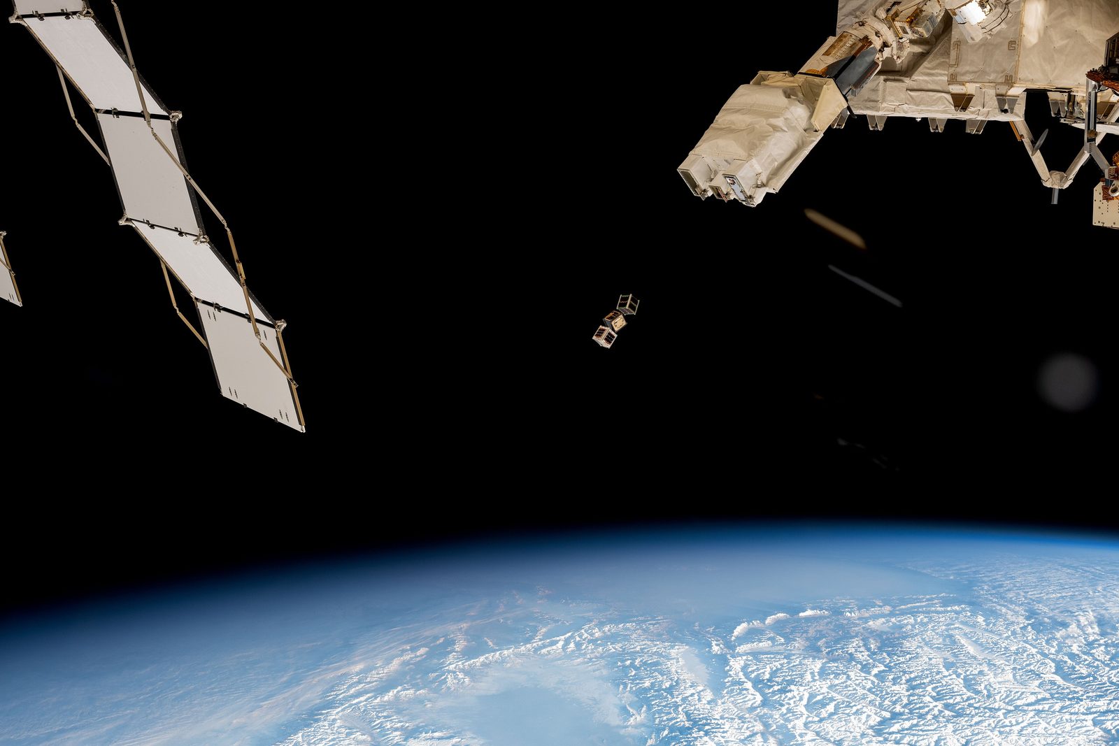 A small satellite deploying from the International Space Station above the Earth