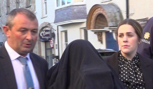 A woman with her head covered arrives at Clonmel District Court escorted by gardai