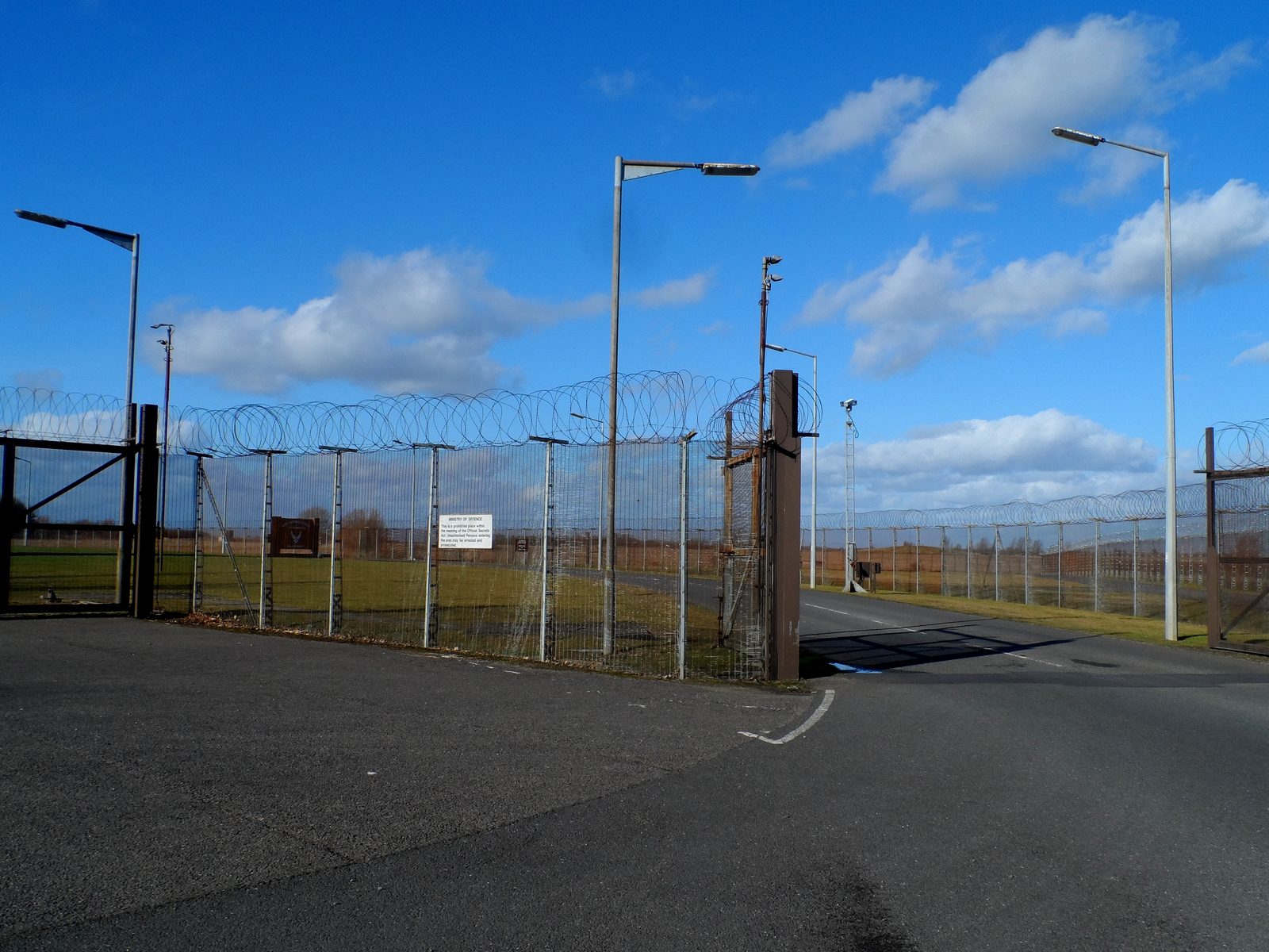 The secured entrance to RAF Molesworth with high fencing and a Ministry of Defence sign